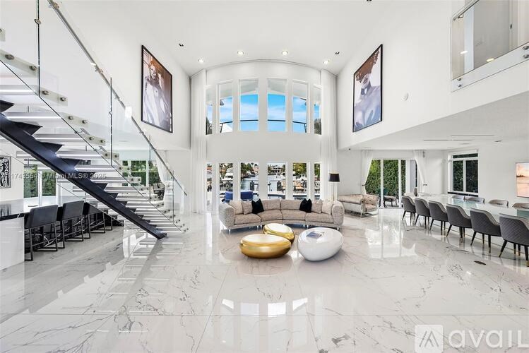 A spacious living room with a staircase and a large window.