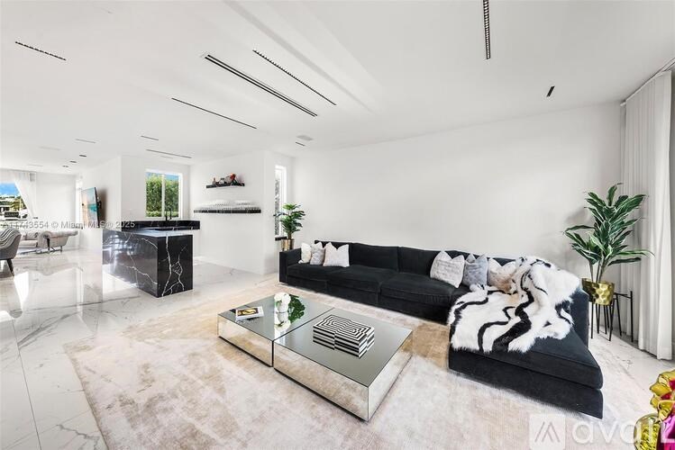 A modern living room with a black and white sofa, a glass coffee table, and a striped throw blanket.