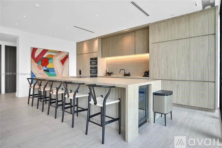 A modern kitchen with a long counter and bar stools.