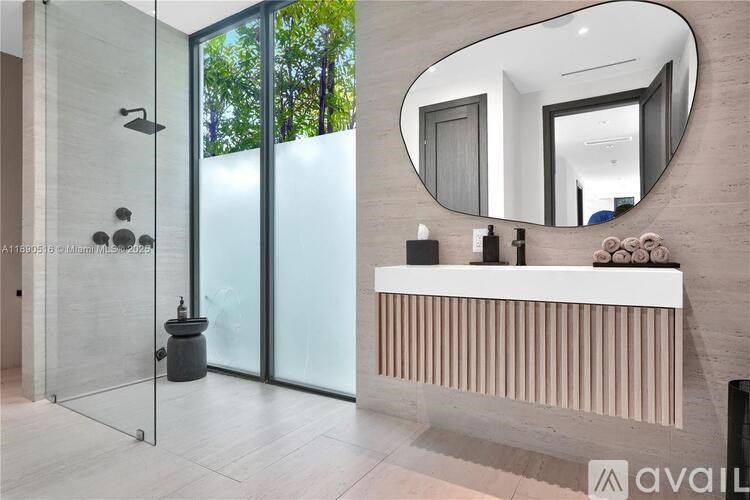 A bathroom with a glass shower and a round mirror above a radiator.