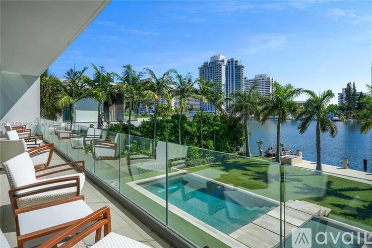 A balcony with chairs and a pool overlooking a cityscape.