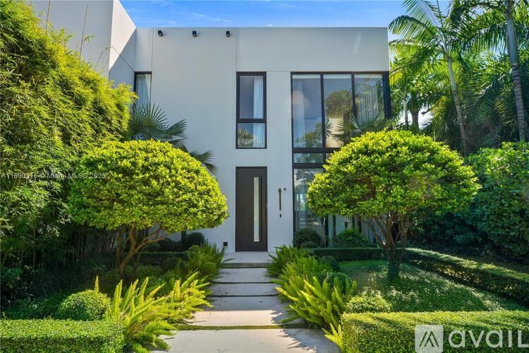 A modern house with a white exterior and a garden in front.