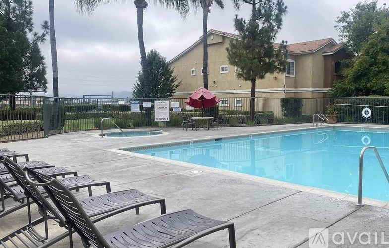 A pool surrounded by lounge chairs and trees.