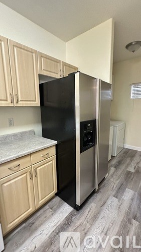 A kitchen with a black refrigerator and wooden cabinets.