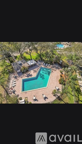 A pool surrounded by trees and lawn chairs.