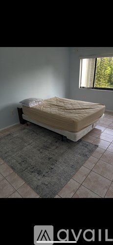 A bed with a white sheet is in a room with a window.