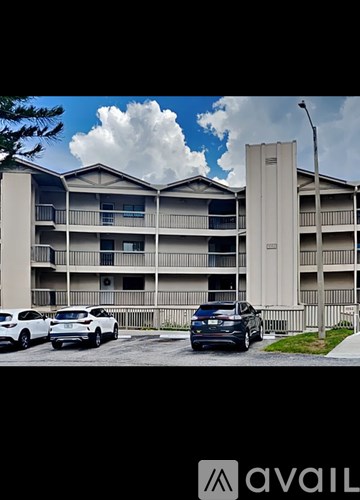 A white car is parked in front of a building with a sign that says "AVAIL".