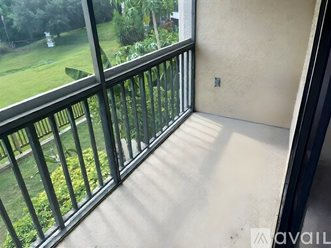 A balcony with a glass railing overlooking a green lawn.