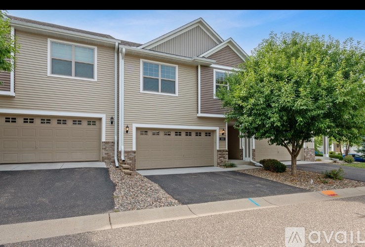 A house with a garage and a tree in front.