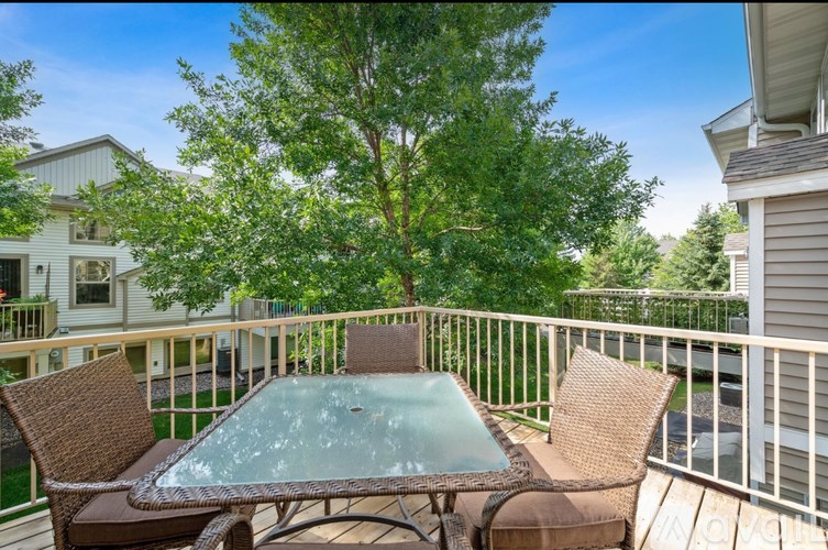 A patio with a glass table and chairs with a tree in the background.