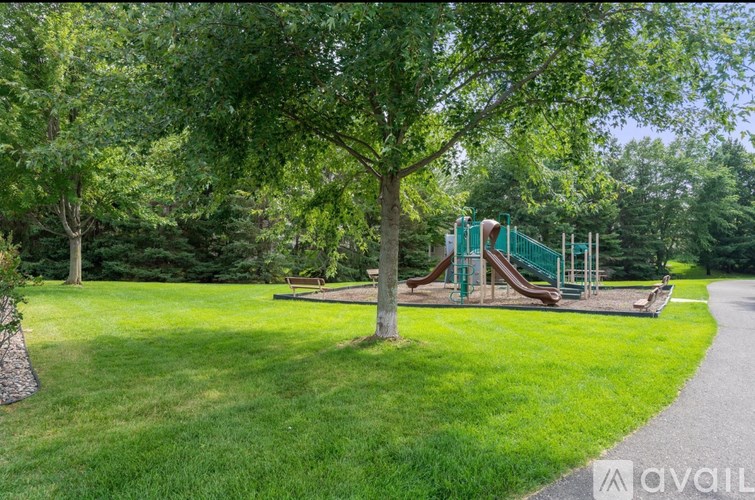 A playground with a slide and a tree in the foreground.