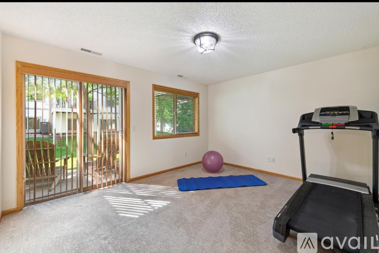 A room with a treadmill, exercise ball, and yoga mat.