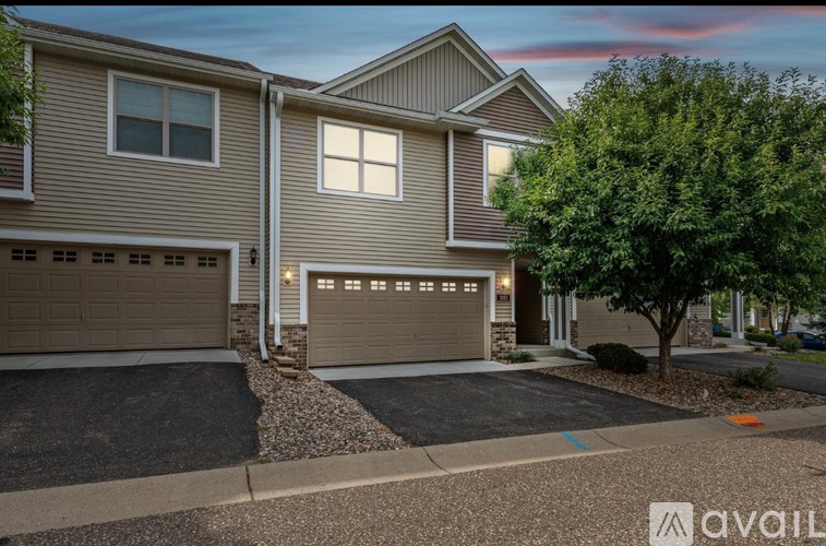 A house with a garage and a tree in front.