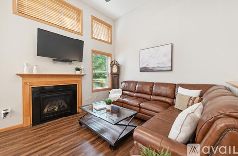 A living room with a brown leather couch and a fireplace.