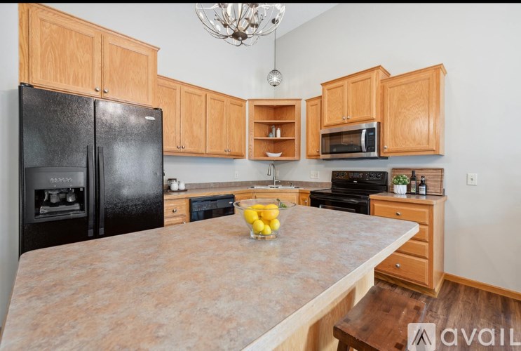 A kitchen with wooden cabinets and a black refrigerator.