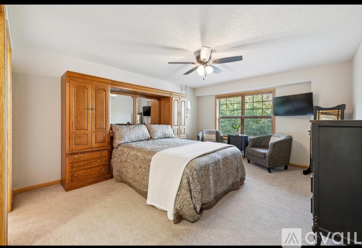 A bedroom with a large bed and a ceiling fan.