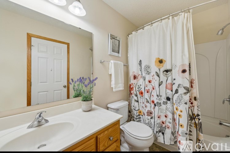 A bathroom with a floral shower curtain and a white toilet.