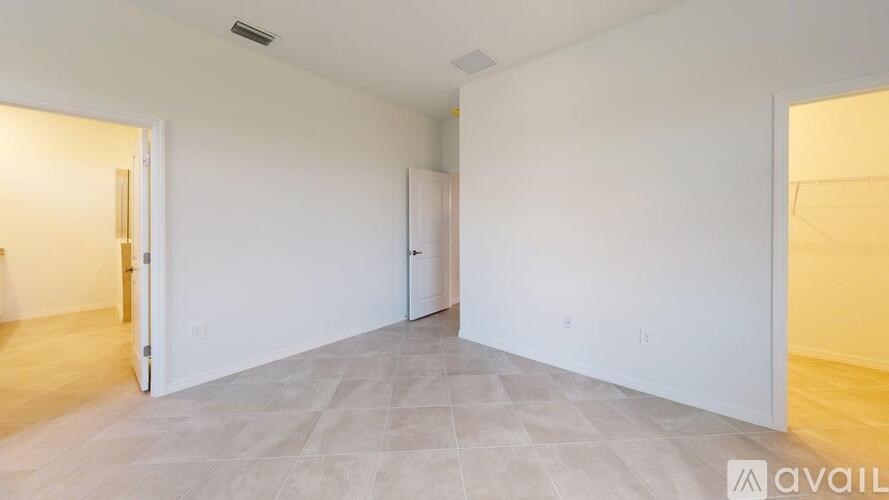 A spacious empty room with tiled flooring and white walls.