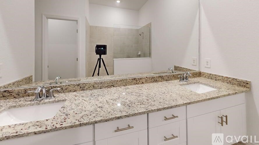 A bathroom with a granite countertop and a camera on a tripod.