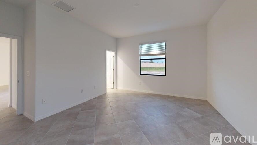 A spacious room with a large window and tiled flooring.