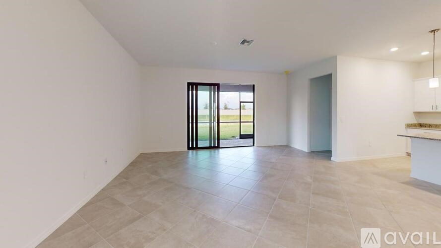A spacious room with a sliding glass door leading to a green outdoor area.