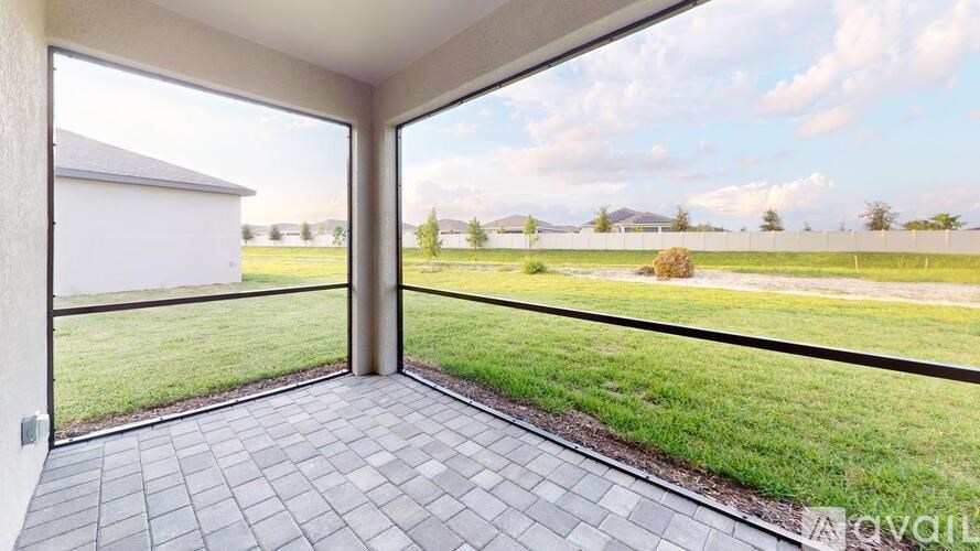 A patio with a tiled floor and a glass door leading to a grassy area.