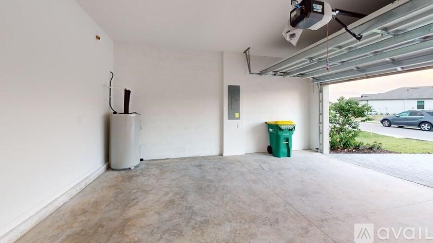 A garage with a white wall and a green trash can.