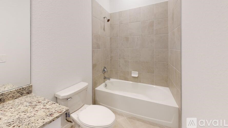 A bathroom with a toilet, tub, and marble countertop.