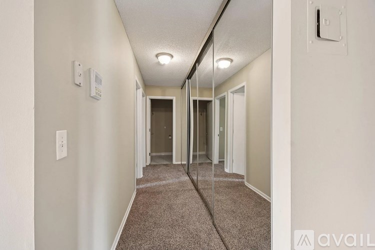 A hallway with a carpeted floor and a mirror on the wall.