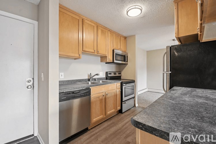 A kitchen with wooden cabinets and a black refrigerator.