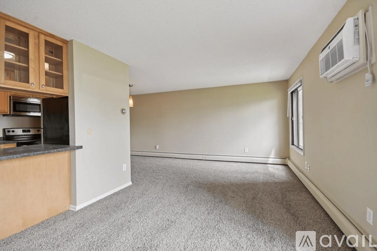 A room with a carpeted floor and a wall-mounted air conditioner unit.