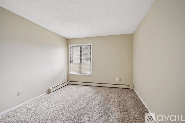 A room with a carpeted floor and a window with blinds.