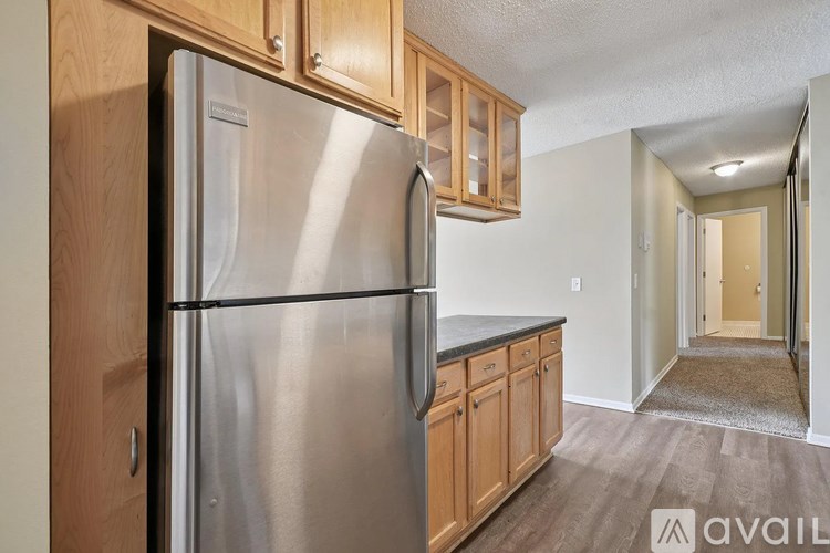A stainless steel refrigerator is in a kitchen with wooden cabinets.