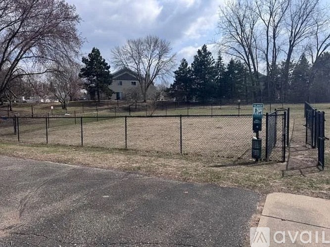 A fenced area with a sign and a tree in the background.