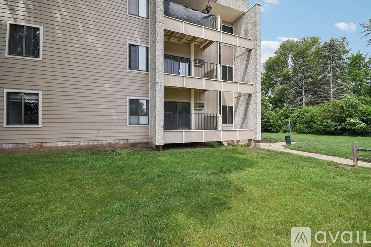 A large grassy area in front of a tan building with a balcony.