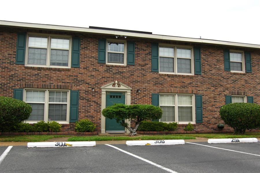 the front of a brick building with green doors and windows