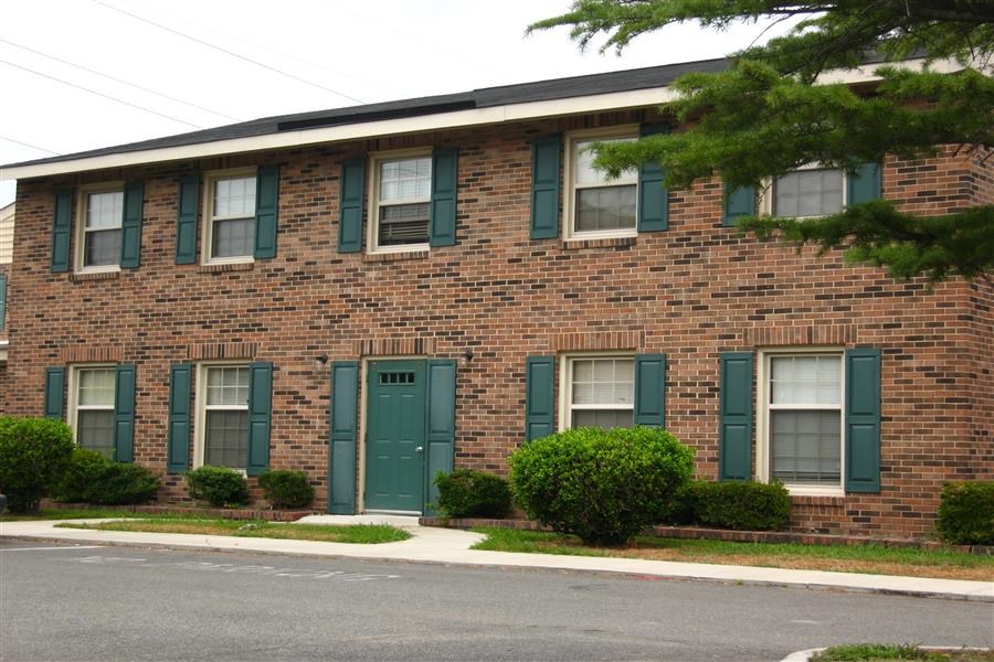 a brick apartment building with green doors and windows