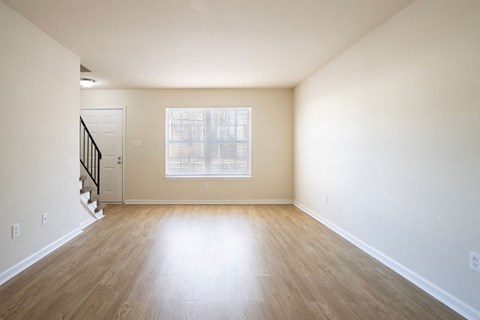 A room with a wooden floor and a staircase.