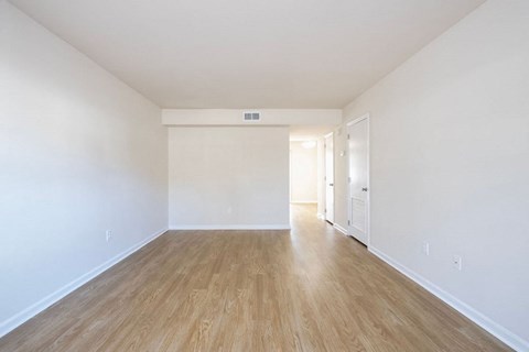 A room with wooden flooring and white walls.