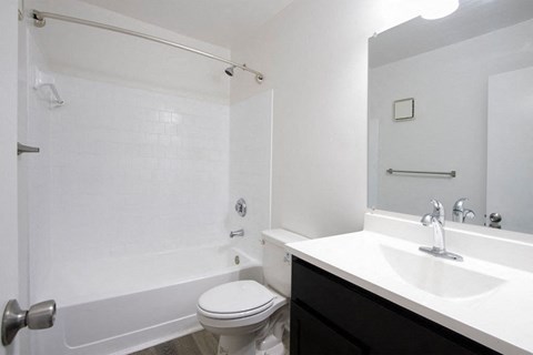 A white bathroom with a toilet, sink, and shower.