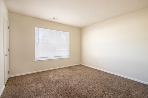 A room with a carpeted floor and a window.
