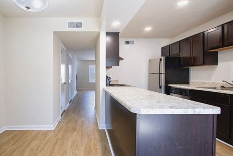 A kitchen with a marble countertop and dark brown cabinets.