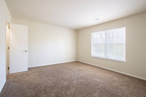 A room with a carpeted floor and a window.