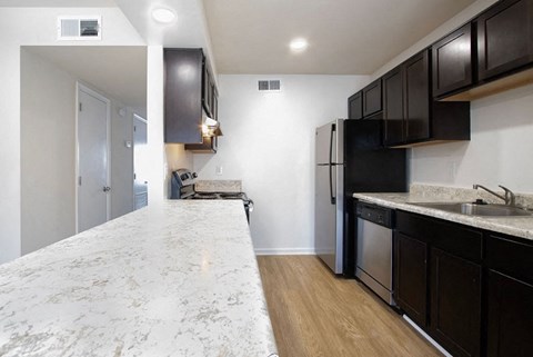A kitchen with a marble counter top and black cabinets.