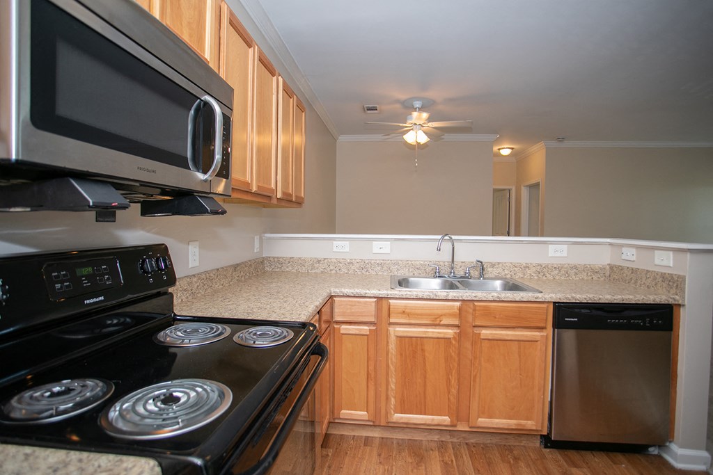 an empty kitchen with a stove microwave and sink