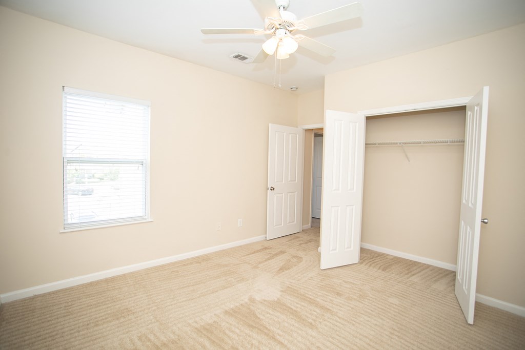 an empty bedroom with a closet and a ceiling fan