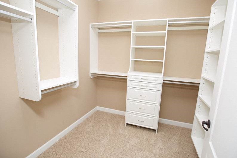 a large closet with white shelves and
