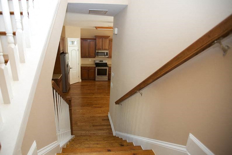 a hallway with stairs and a kitchen in a house