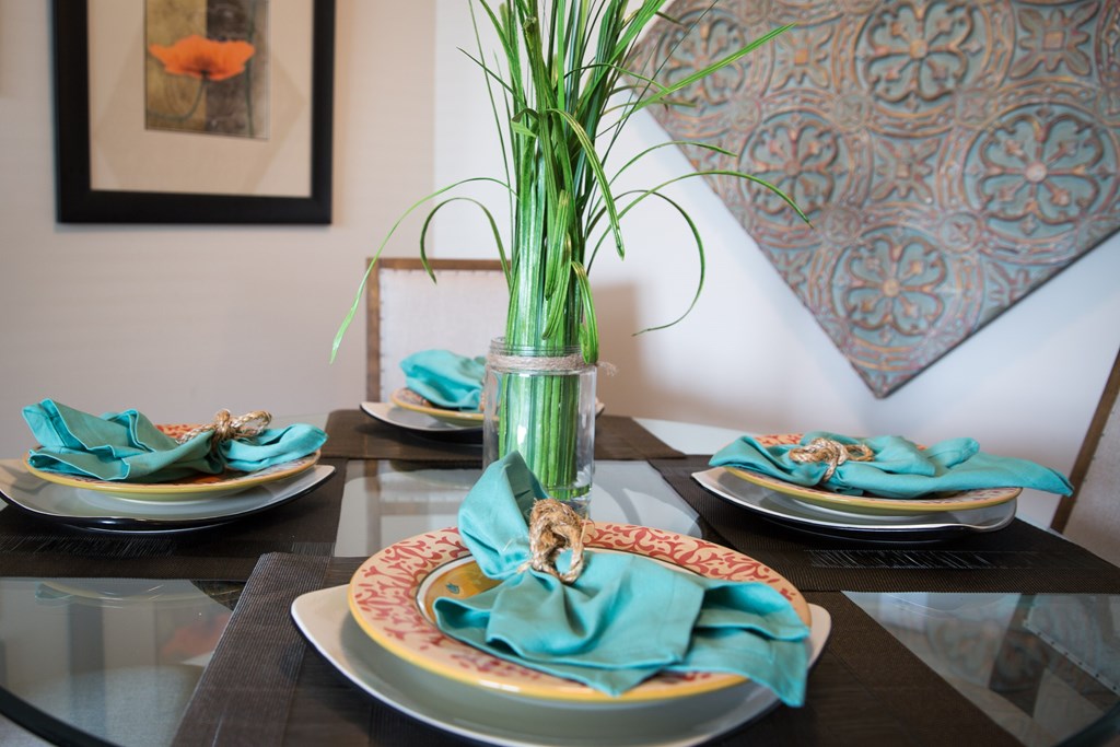 a dining table with plates and a vase with flowers on it