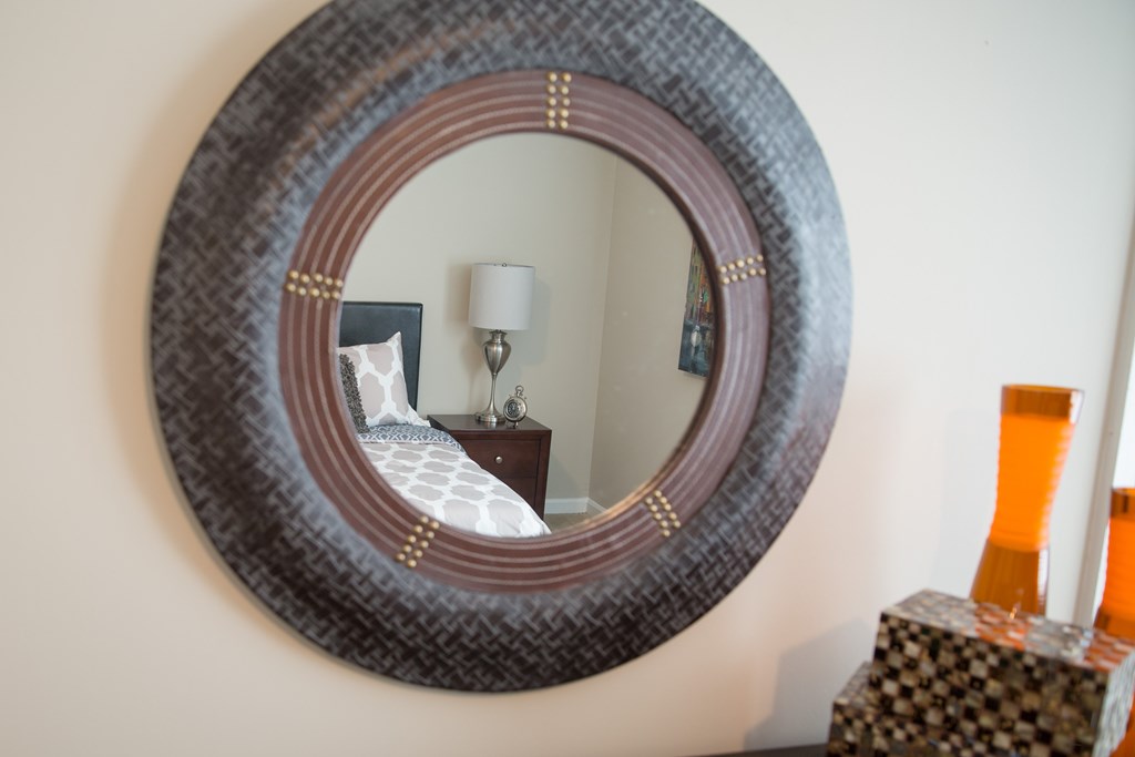 a mirror hanging on a wall above a bed